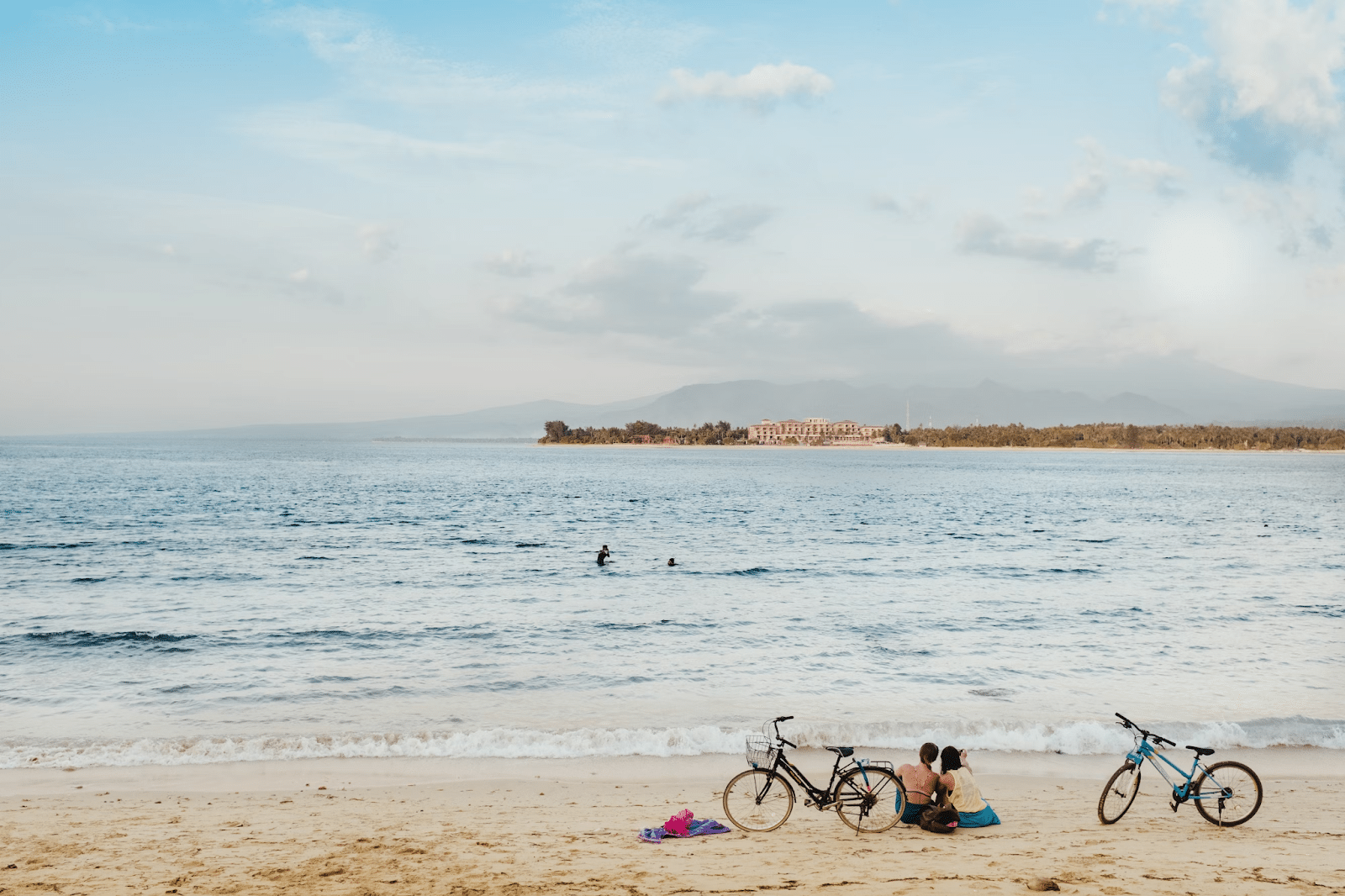 Ein Strand von Gili Meno, die Strandbesucher:innen sind mit dem Fahrrad unterwegs.